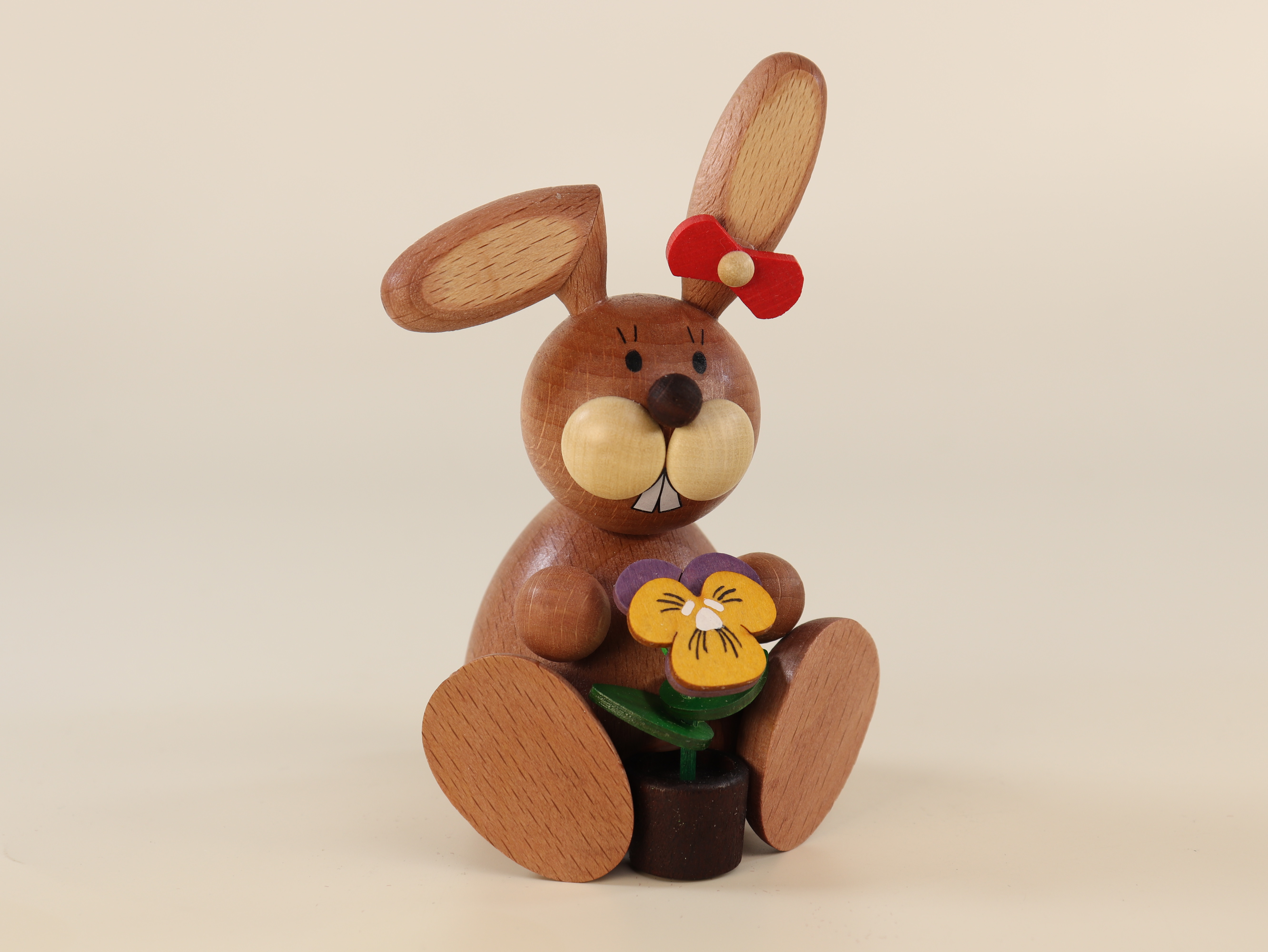 Sitzende Häsin mit Blume als Osterschmuck 