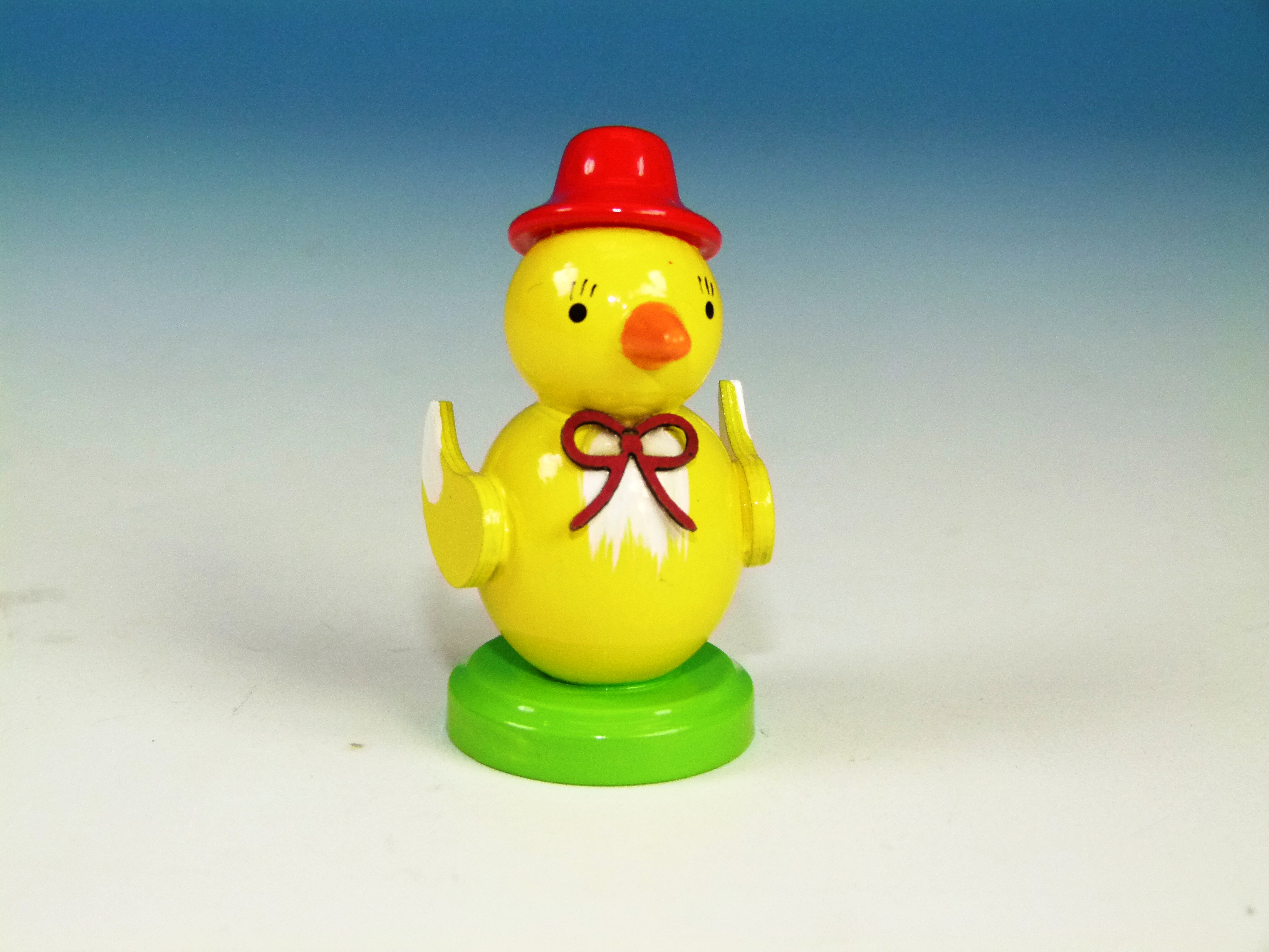 Tisch-Deko Holzfigur Küken mit rotem Hut und roter Schleife auf einem Sockel Küken mit rotem Hut und roter Schleife auf einem Sockel zum Hinstellen